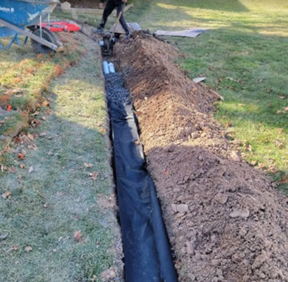 Exterior foundation drain with waterproofing membrane and perforated pipe in a trench